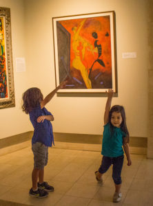 A young boy and young girl imitating a work of art in a museum.